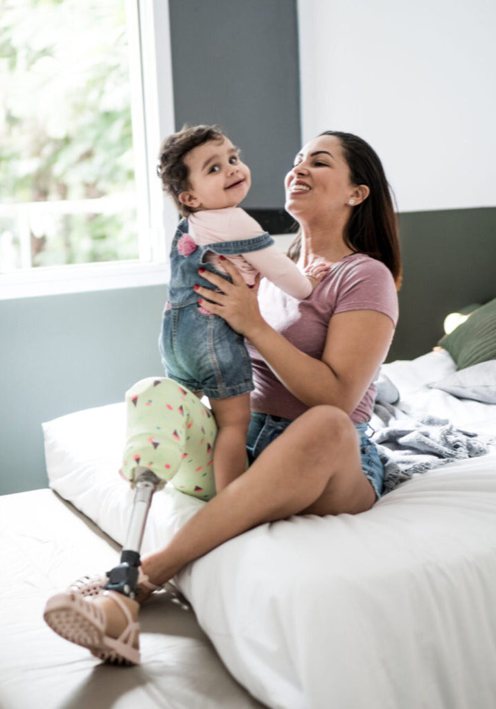 Decorative: A white woman with a prosthetic leg playing with her baby